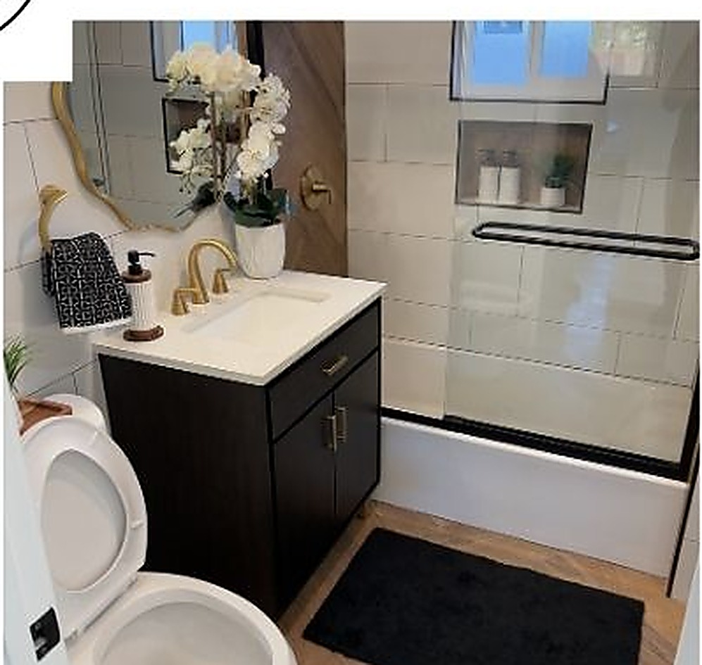 Spa-style primary bathroom with a dark vanity, brass fixtures, and glass shower surround