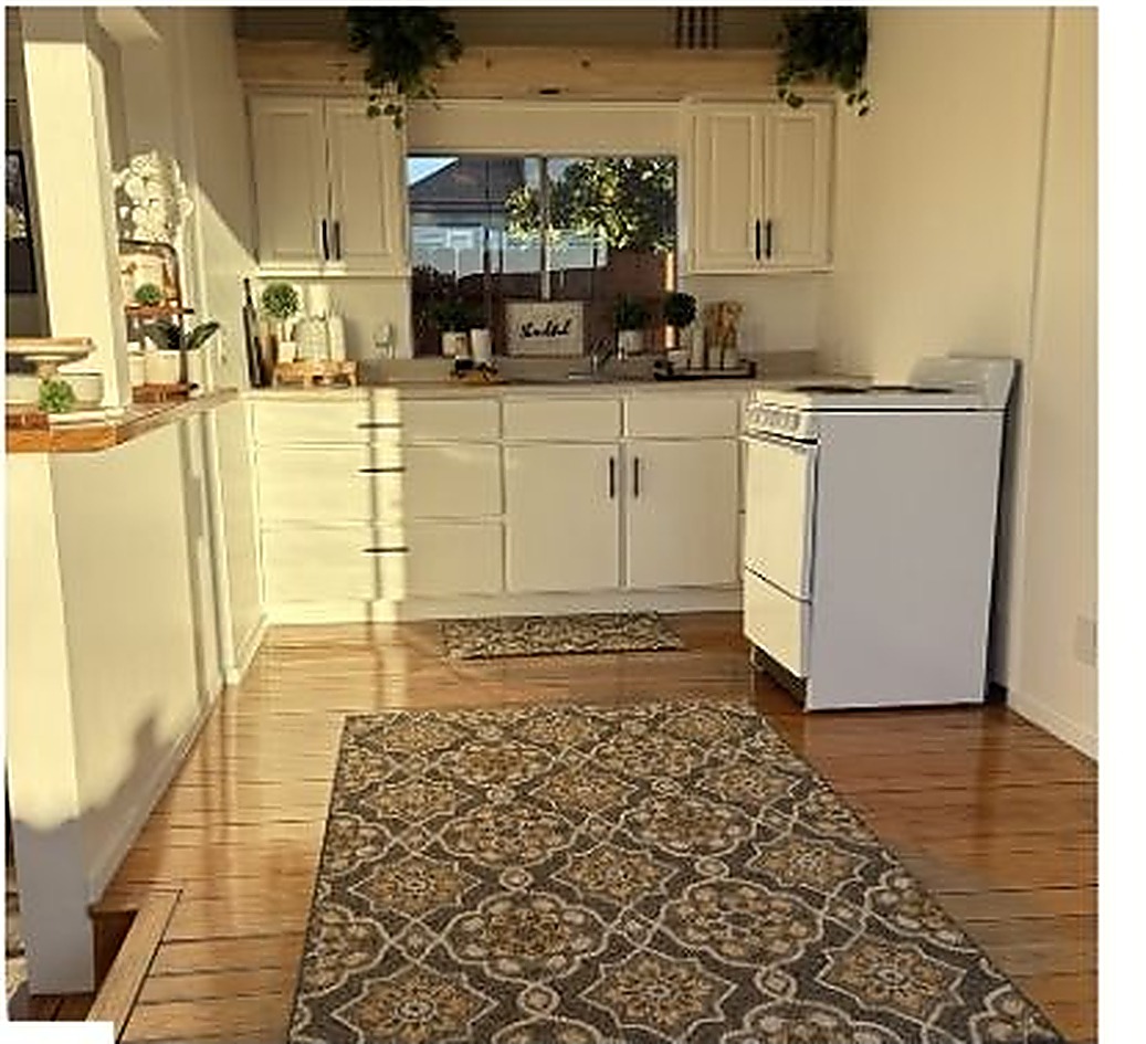 Sunlit farmhouse kitchen with white cabinetry and a patterned area rug