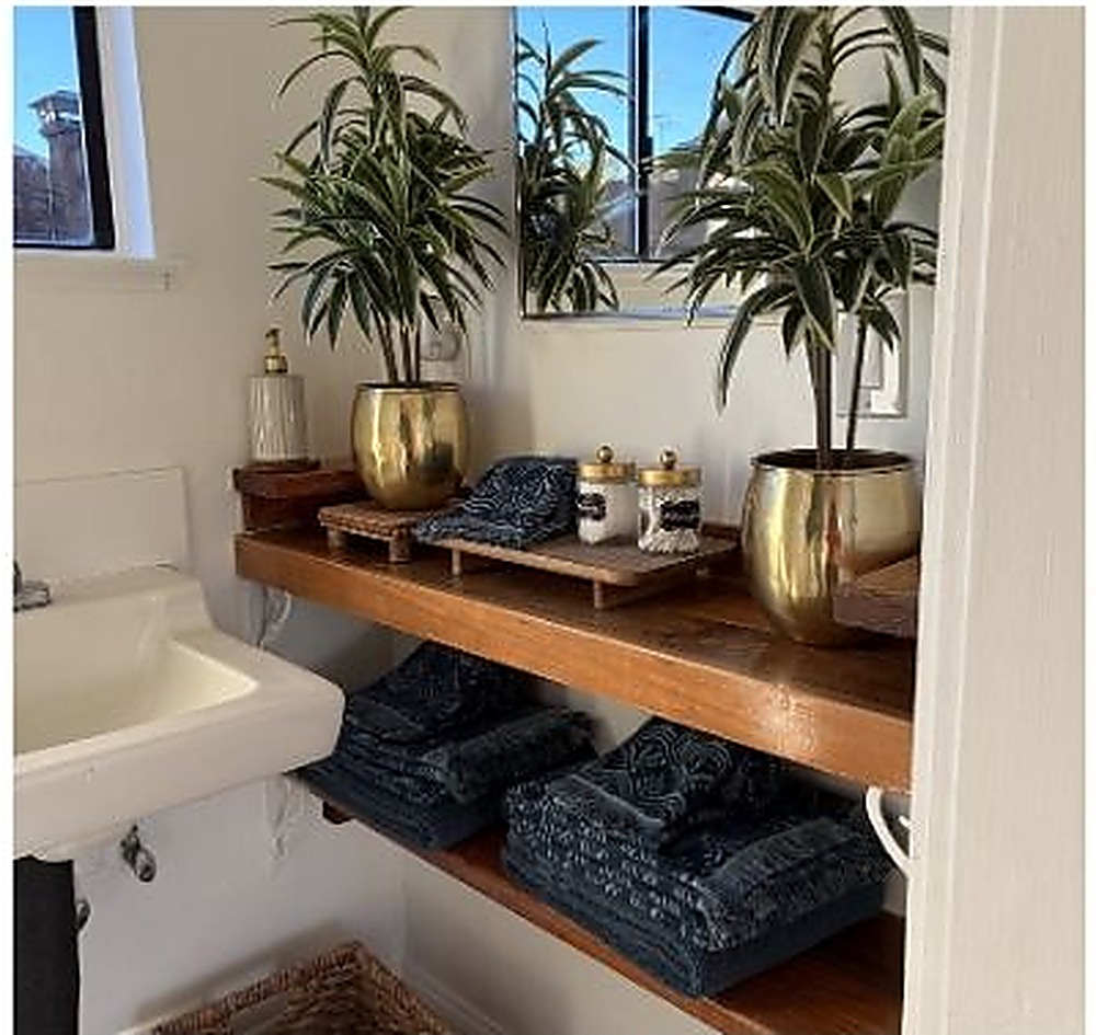 Built-in bathroom shelving styled with brass planters and folded towels
