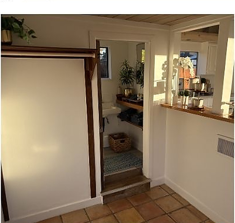 Terracotta-tiled entry passage leading to a bright kitchenette